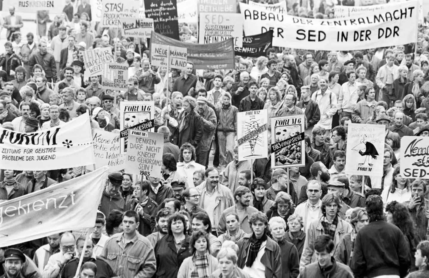 historsches Schwarz-Weiß-Foto zeigt Menschenmasse auf einer Demonstration in der DDR mit Protest-Bannern und Schildern