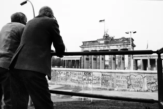 Schwarz-Weiß-Foto, zwei Männer stehen vor Mauer vor dem Brandenburger Tor