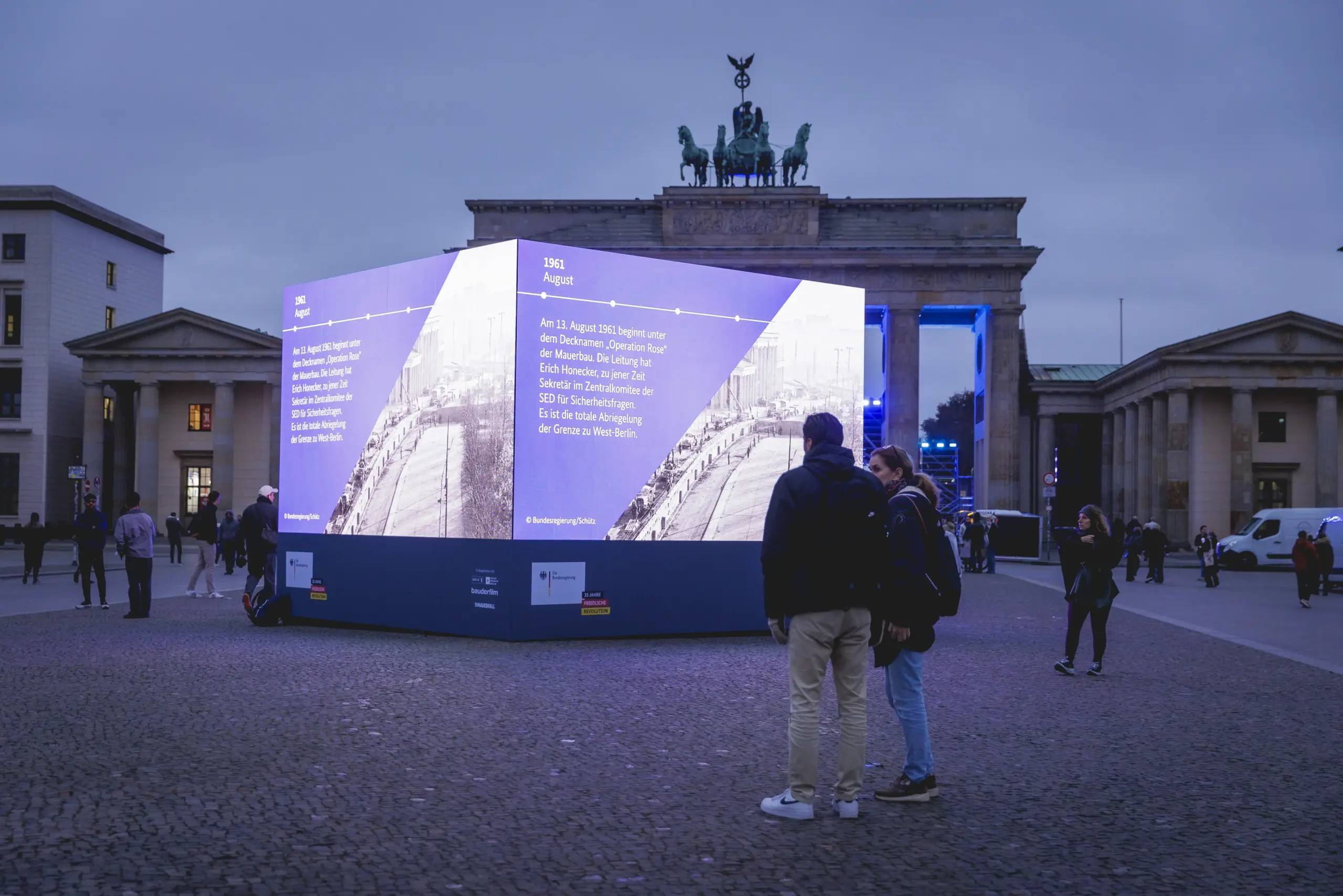 Video-Cube bei Nacht vor dem Brandenburger Tor, Menschen betrachten die Videos